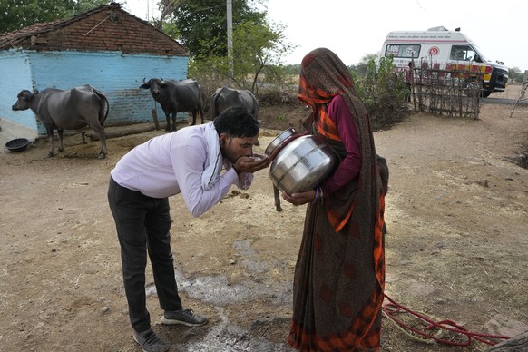 A village woman gives water to Sunil Kumar Naik, an ambulance driver, to quench his thirst during a heat wave, on the way to a hospital, near a village in Banpur in the Indian state of Uttar Pradesh,  ...