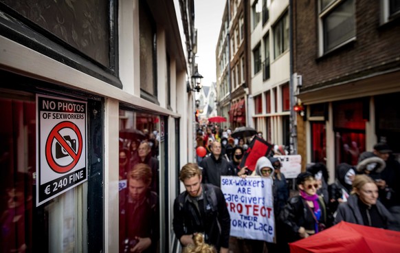 epa10927620 Demonstrators hold placards during a parade through Amsterdam, The Netherlands, 19 October 2023. Red Light District residents, entrepreneurs and sex workers staged a protest against the mo ...