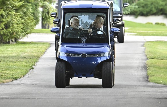 Russian President Vladimir Putin, right, takes Indian Prime Minister Narendra Modi for a ride in a electric golf cart during an informal meeting at Novo-Ogaryovo residence, outside Moscow, Russia, Mon ...
