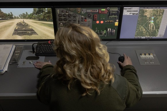 A Ukrainian military member looks at screens as a Ukrainian serviceman practices his driving skills on an armoured vehicle simulator at the Ukrainian Ground Forces training center in an undisclosed lo ...