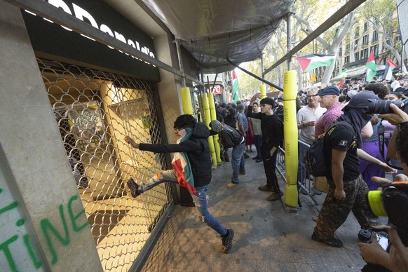 epa12431173 A man tries to break the door of a McDonals during a demonstration following a rally organized in support of Palestine in Barcelona, Spain, 04 October 2025. EPA/MARTA PEREZ