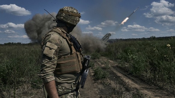 A Ukrainian soldier watches a Grad multiple launch rocket system firing shells with flyers near Bakhmut, Donetsk region, Ukraine, Sunday, Aug. 13, 2023. (AP Photo/Libkos)