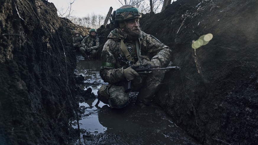 Ukrainian soldiers in a trench under Russian shelling on the frontline close to Bakhmut, Donetsk region, Ukraine, Sunday, March 5, 2023. (AP Photo/Libkos)