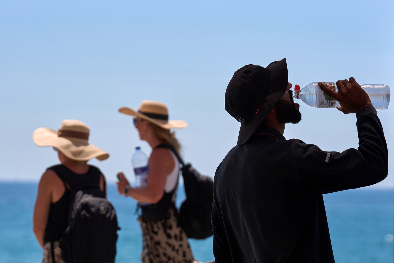 FILE - A tourist drinks water on a hot day at the beach in Barcelona, Spain, July 2, 2025. (AP Photo/Emilio Morenatti, File)
Europe Heat Deaths