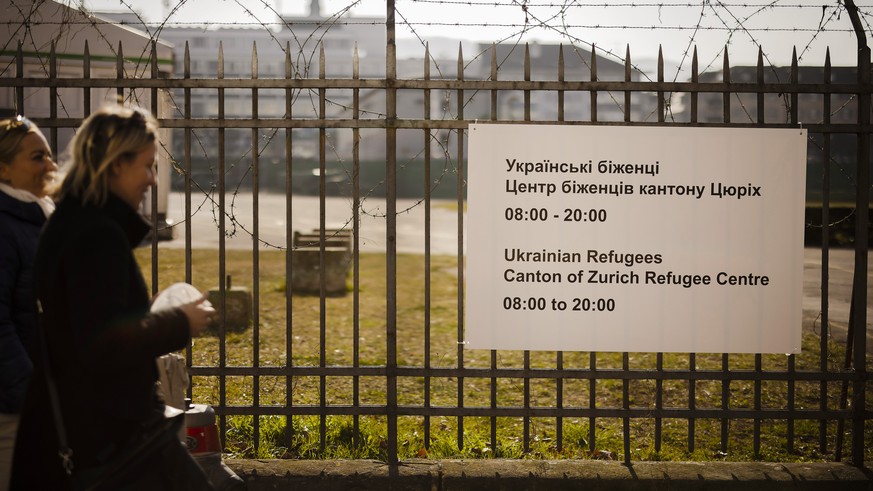People walk past a sign reading "Ukrainian Refugees. Canton of Zurich Refugee Center", following Russia's invasion of Ukraine, in Zurich, Switzerland on March 9, 2022. (KEYSTONE/Michael ...