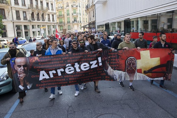 Protesters hold a banner with the portrait of the Swiss Interior Minister Alain Berset and the Swiss hero William Tell during a demonstration march against civil restrictions and the coronavirus COVID ...