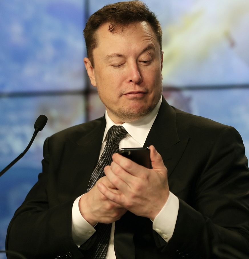 FILE - Elon Musk founder, CEO, and chief engineer/designer of SpaceX jokes with reporters as he pretends to search for an answer to a question on a cell phone during a news conference after a Falcon 9 ...