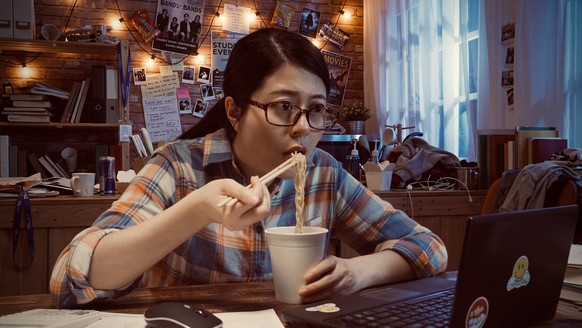 Student eating instant ramen while studying. 
Symbolbild.