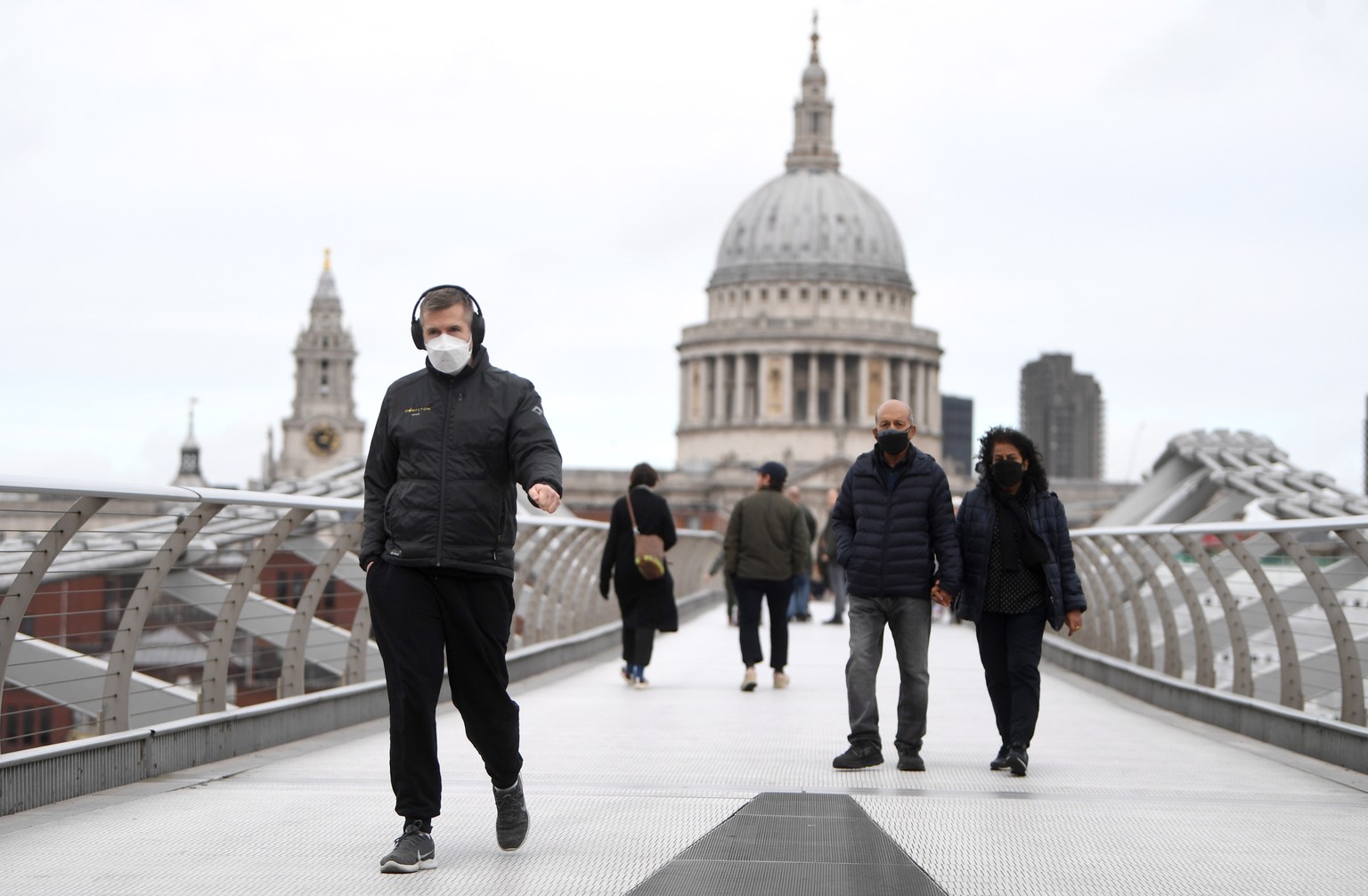 epa09664723 People cross Milleneum Bridge wearing protective masks in London, Britain, 03 January 2022. A number of new Nightgale hubs are being prepared in existing hospitals to prepare for Omicron v ...