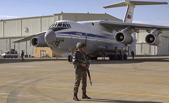 epa10603768 A handout still image taken from a handout video provided by the Russian Defence ministry press-service shows a Russian serviceman standing guard near a military aircraft during a military ...