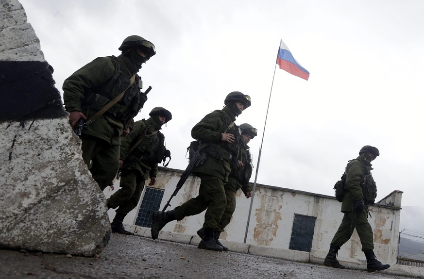 epa04113222 Armed men in military uniform march outside the territory of a Ukrainian military unit in the village of Perevalnoye, outside Simferopol, Ukraine, 07 March 2014. The Crimea&amp;#039;s parl ...