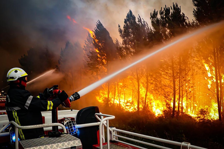 This photo provided Friday July 15, 2022 by the fire brigade of the Gironde region (SDIS 33) shows firefighters using hose to fight a wildfire near Landiras, southwestern France, Thursday, July 14, 20 ...