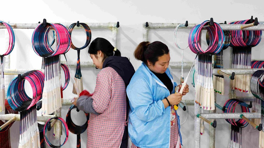 Deux ouvrières fabriquent ici des raquettes de badminton destinées à l'exportation, le 16 mars 2026 à Suqian (est), dans la province chinoise du Jiangsu.