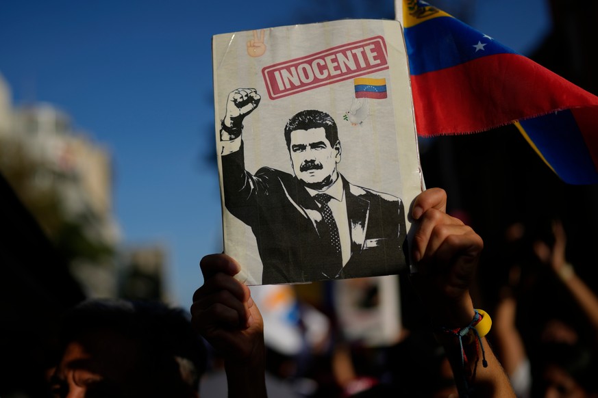 A government supporter holds an image of former President Nicolás Maduro during a march calling for his release and of his wife Cilia Flores, a month after U.S. forces captured them, in Caracas, Venez ...