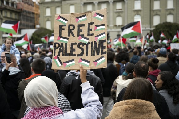 Protesters hold Palestinian flags and placards during an authorized rally in solidarity with Palestine, at the Federal square, in Bern, Switzerland, on Saturday, October 28, 2023. Thousands of Israeli ...