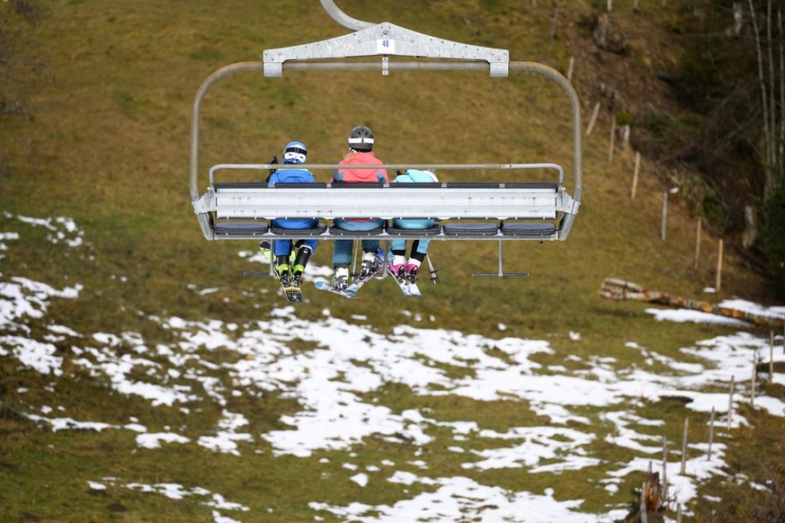 Skiers ride the chairlift between La Rasse et Chaux Ronde above a snowless field, at 1600 meters above sea level, in the alpine resort of Villars-sur-Ollon, Switzerland, Saturday, December 31, 2022. T ...