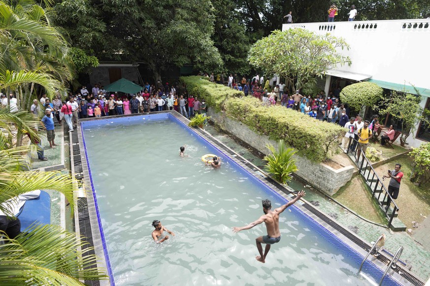 Protesters swim as onlookers wait at a swimming pool in the president&#039;s official residence a day after it was stormed in Colombo, Sri Lanka, Sunday, July 10, 2022. Sri Lanka