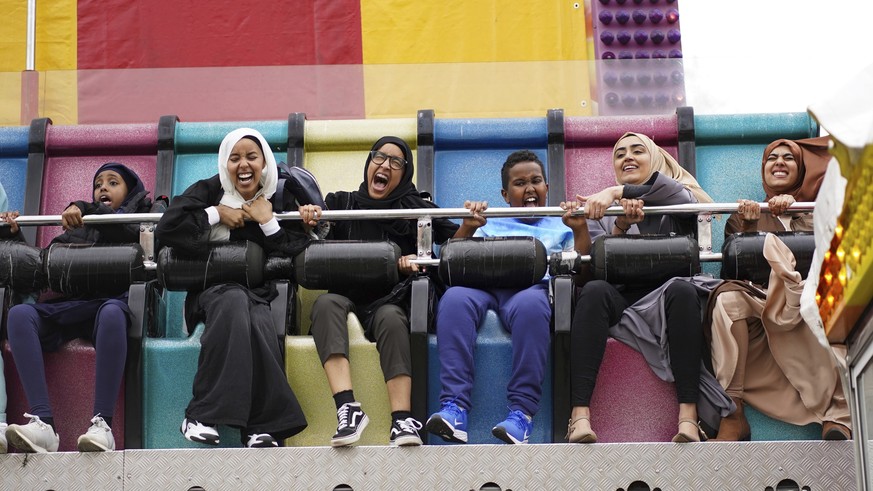Muslims enjoy a theme park ride as they celebrate Eid al-Fitr as the holy month of Ramadan comes to an end, at Small Heath Park, in Birmingham. England, Monday May 2, 2022. (Jacob King/PA via AP)