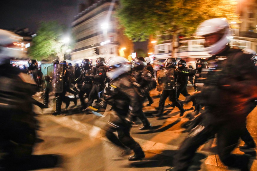 epa09907568 Policemen run towards protesters participating in a demonstration after the announcement of French presidential election results at Place de la Republique in Parisin Paris, France, 24 Apri ...