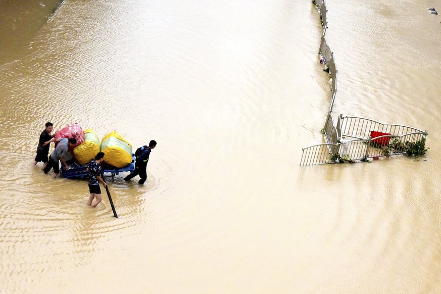 In this photo released by Xinhua News Agency, residents move their belongings across a flooded street in Zhengzhou in central China's Henan province on Wednesday, July 21, 2021. China's mili ...