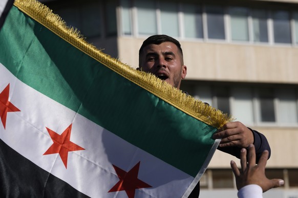 A Syrian man waves a flag during a spontaneous demonstration celebrating the fall of the Assad regime, in Nicosia, Cyprus, Sunday, Dec. 8, 2024. (AP Photo/Petros Karadjias)