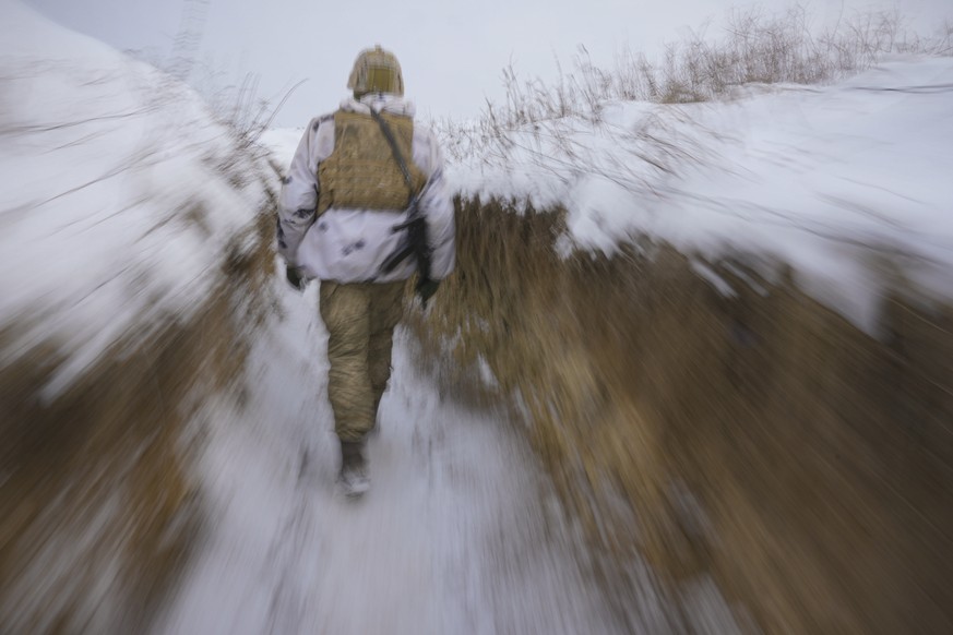 FILE - A Ukrainian serviceman walks through a trench on the front line in the Luhansk area, eastern Ukraine, Jan. 27, 2022. When some 100,000 Russian troops have closed in on the border of Ukraine ove ...