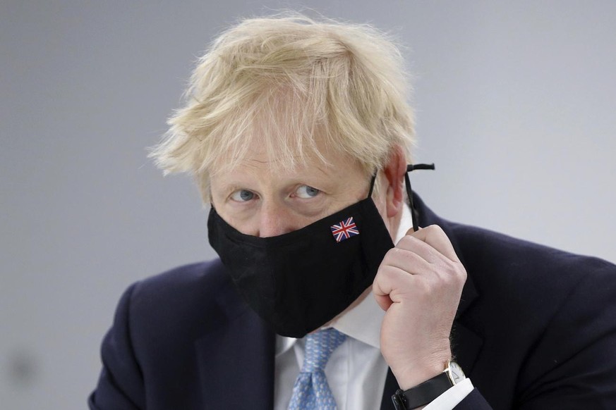 Britain's Prime Minister Boris Johnson adjusts his face mask during a visit to Severn Trent Academy in Coventry, Britain, Friday May 7, 2021. (Phil Noble/Pool via AP)