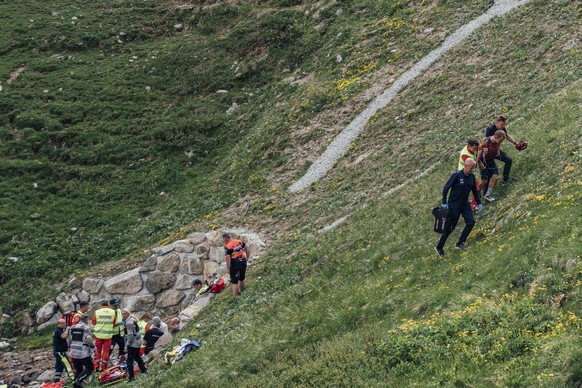Gino Maeder from Switzerland of Bahrain Victorious, left, recieves medical attention after crashing during the fifth stage, a 211 km race from Fiesch to La Punt, at the 86th Tour de Suisse UCI World T ...