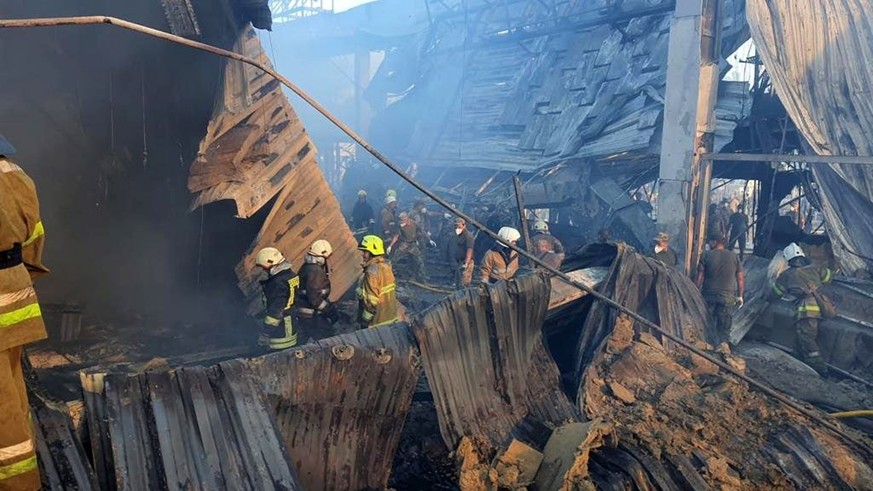 epa10037220 A handout photo released by the press service of the State Emergency Service (SES) of Ukraine shows firefighters and rescue services working to extinguishe a fire at a shopping center in K ...