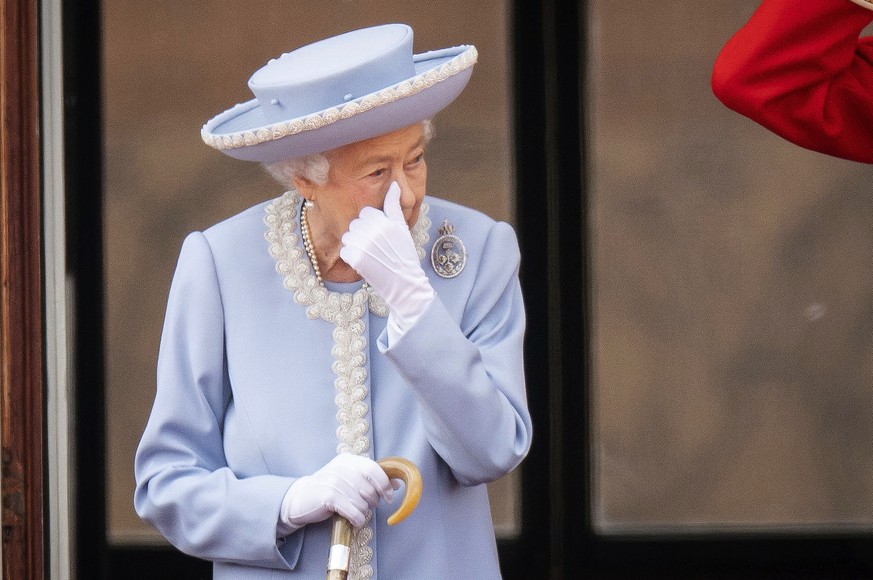Queen Elizabeth II wipes her eye as she and the Duke of Kent watch from the balcony of Buckingham Place after the Trooping the Color ceremony in London, Thursday, June 2, 2022, on the first of four da ...