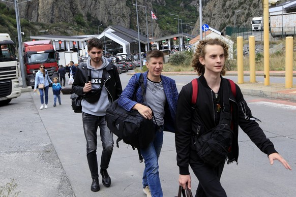 FILE A group of young Russians walk along the border crossing Verkhny Lars between Georgia and Russia on Friday, Sept. 23, 2022. Long lines of vehicles have formed at a border crossing between Russia& ...