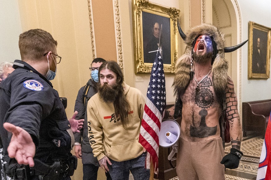 FILE - Supporters of President Donald Trump, including Jacob Chansley, right with fur hat, are confronted by U.S. Capitol Police officers outside the Senate chamber inside the Capitol during the capit ...