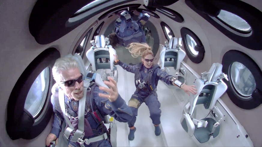 epa09339453 A framegrab from a video made available by Virgin Galatic shows Sir Richard Branson (L) aboard SpaceShip Two Unity 22 as they attain zero gravity during their flight after take off from Sp ...