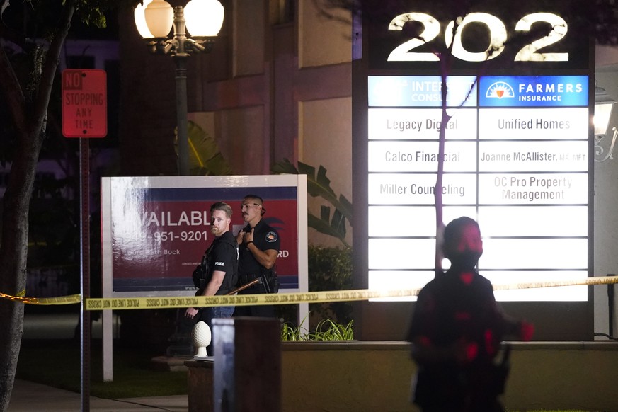 Police officers stand outside a business building where a shooting occurred in Orange, Calif., Wednesday, March 31, 2021. Police say several people were killed, including a child, and the suspected sh ...