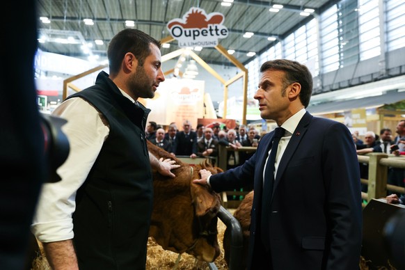 epa11914750 French President Emmanuel Macron pets Limousin cow breed Oupette, the muse of the agricultural show, next to farmer Alexandre Humeau during the opening day and inauguration of the 61st Int ...
