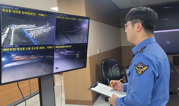 epa11052161 A South Korean Coast Guard officer monitors closed-circuit television feeds showing beaches and coastal areas, inside the regional headquarters in Donghae, after minor tsunamis caused by a ...