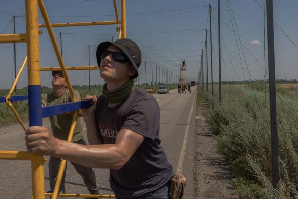 Ukrainian servicemen install anti-drone nets over a road at an undisclosed location in the eastern Donetsk region on July 8, 2025, amid the Russian invasion of Ukraine. (Photo by Roman PILIPEY / AFP)
