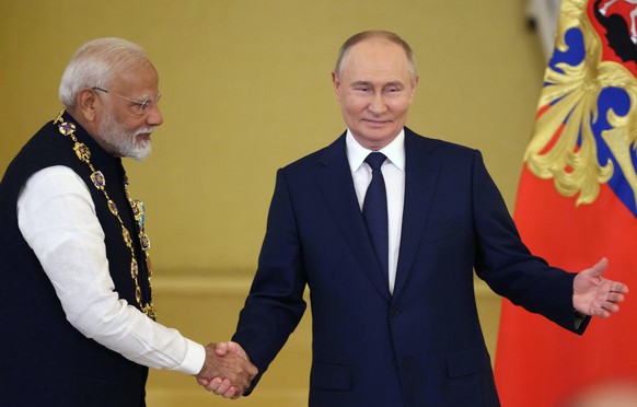 epa11468165 Russian President Vladimir Putin (R) awards Indian Prime Minister Narendra Modi with the Order of St. Andrew the Apostle the First-Called during their meeting in the Kremlin in Moscow, Rus ...
