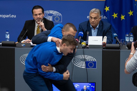 epa11649205 Security officers intercept a man disrupting the press conference of Hungarian Prime Minister Viktor Orban ahead of a plenary session at the European Parliament in Strasbourg, France, 08 O ...