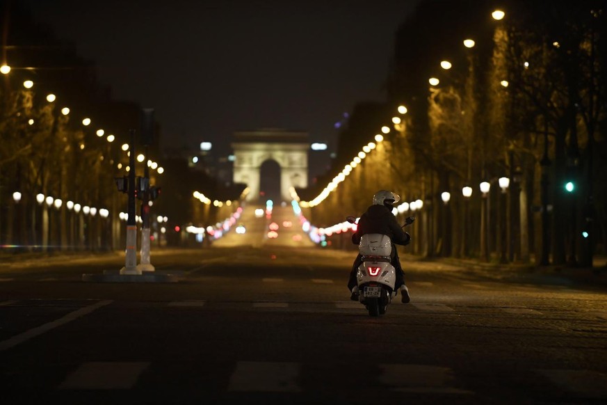 epa08310786 A man drives a Vespa motorcycle on the nearly empty Champs Elysees avenue at night, while France is under lockdown in an attempt to stop the widespread of the SARS-CoV-2 coronavirus causin ...