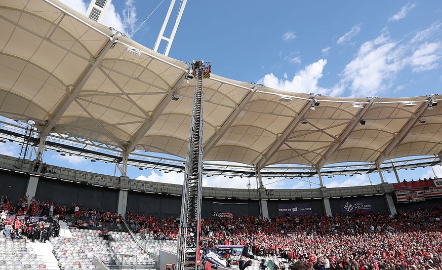 TOULOUSE, FRANCE - APRIL 06: Members of the fire brigade work to rescue a parachutist who became caught on the roof of the stadium as he was delivering the match ball prior to the Investec Champions C ...