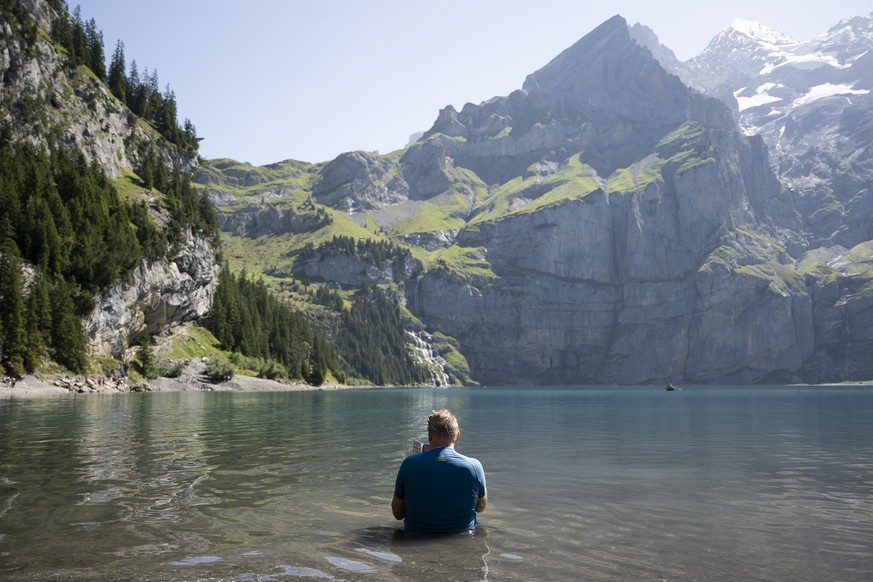 KEYPIX - A person sitting in the lake of Oeschinen "Oeschinensee" (1578 meters above sea), during a very hot summer day, above Kandersteg, in the Bernese Oberland, this August 9, 2025. Accor ...