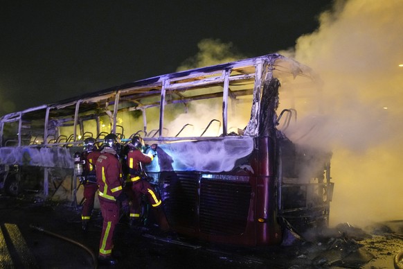 Firefighters use a water hose on a burnt bus in Nanterre, outside Paris, France, Saturday, July 1, 2023. French President Emmanuel Macron urged parents Friday to keep teenagers at home and proposed re ...