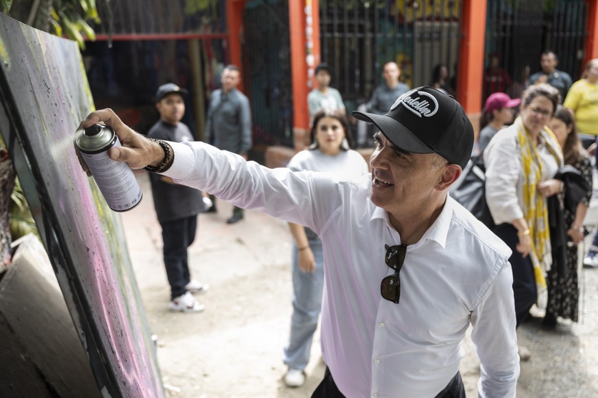epa10792680 Swiss Federal President Alain Berset sprays his name on a blackboard after visiting the Cultural Center Casa Kolacho in the Comuna 13 neighborhood, in Medellin, Colombia, 09 August 2023. C ...