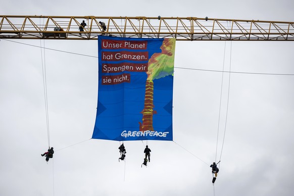 Greenpeace-Aktivisten entrollen auf einem Baukran auf dem Bundesplatz ein Transparent, am Samstag, 13. Mai 2023, in Bern. (KEYSTONE/Peter Klaunzer)
