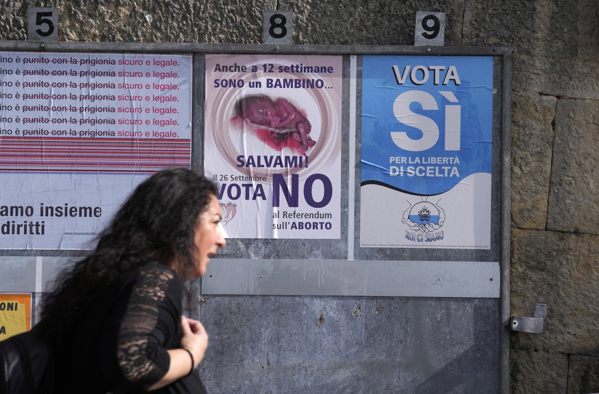 A woman walks past posters for the abortion referendum in San Marino, Sunday, Sept. 26, 2021. Tiny San Marino is one of the last countries in Europe which forbids abortion in any circumstance �?? a ba ...