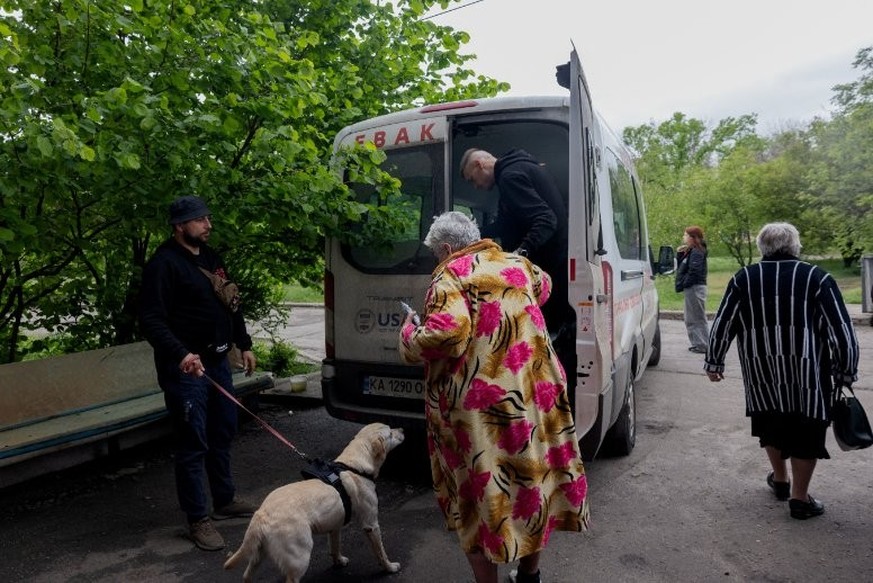 Eduard Skoryk (à droite) et Roman Bugayov (à gauche) de East SOS aident une femme à évacuer à Kramatorsk, dans la région orientale de Donetsk, le 10 mai 2025. Les autorités régionales appellent réguli ...