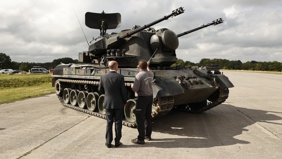 epa10137731 German Chancellor Olaf Scholz is shown an anti-aircraft gun tank Gepard, by Juergen Schoch the lead trainer for the Gebhard system, during his visit a training facility of the arms-maker K ...