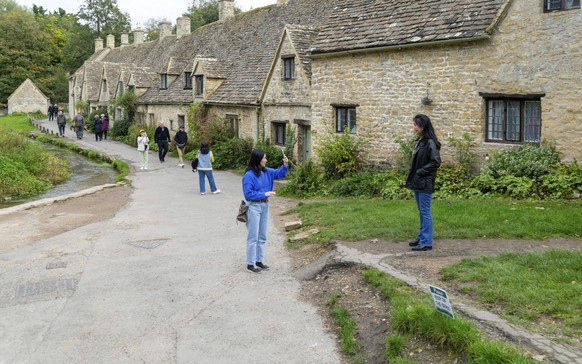A Beautiful shot of stone cottage with a green garden and a river in Bibury Village