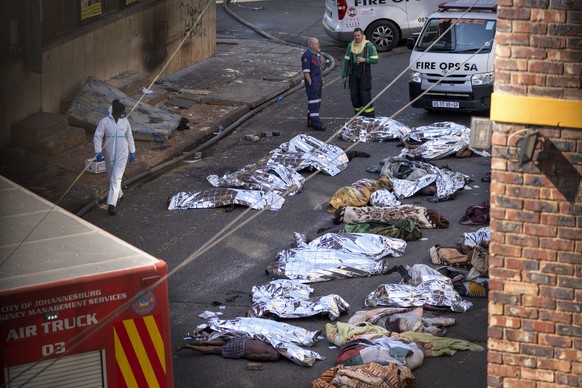 Medics stand by the covered bodies of victims of a deadly blaze in downtown Johannesburg, Thursday, Aug. 31, 2023. Dozens died when a fire ripped through a multi-story building in Johannesburg, South  ...